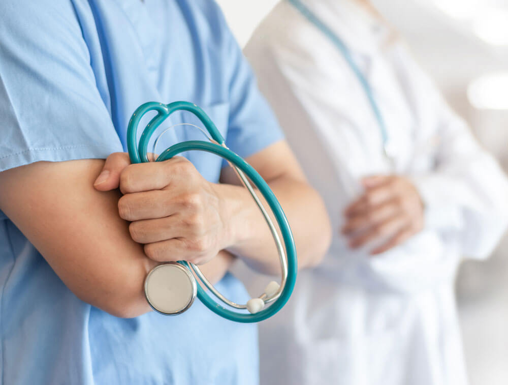 doctor in scrubs with crossed arms and stethoscope