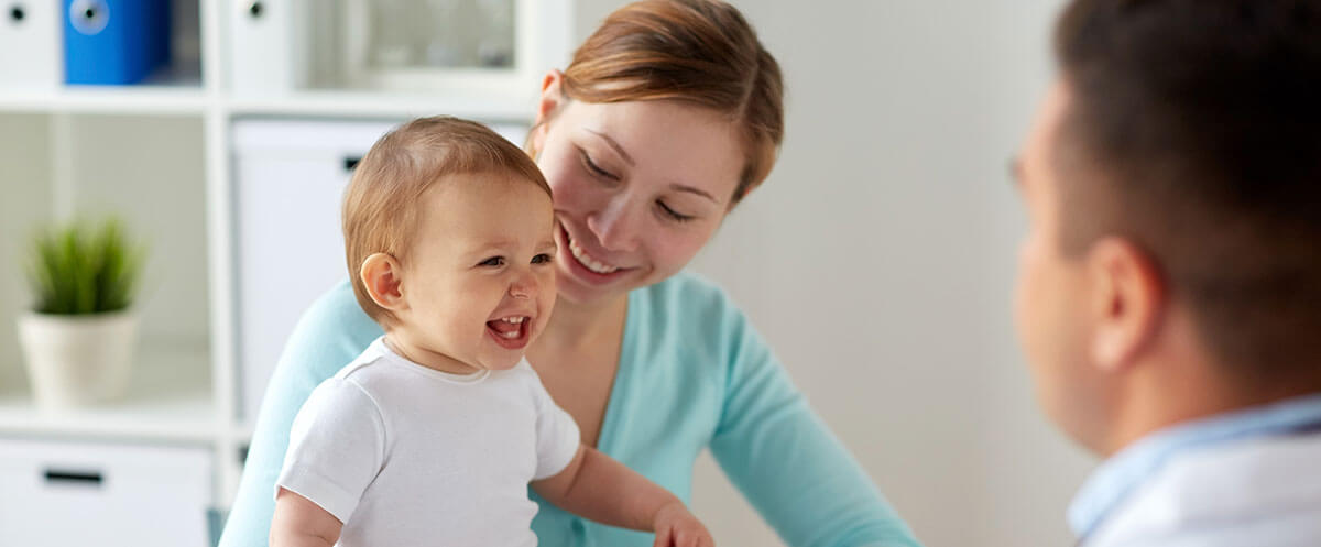 mother and laughing baby with doctor