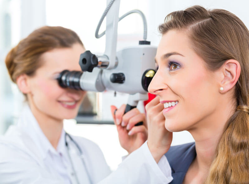 doctor examining a smiling woman's ear