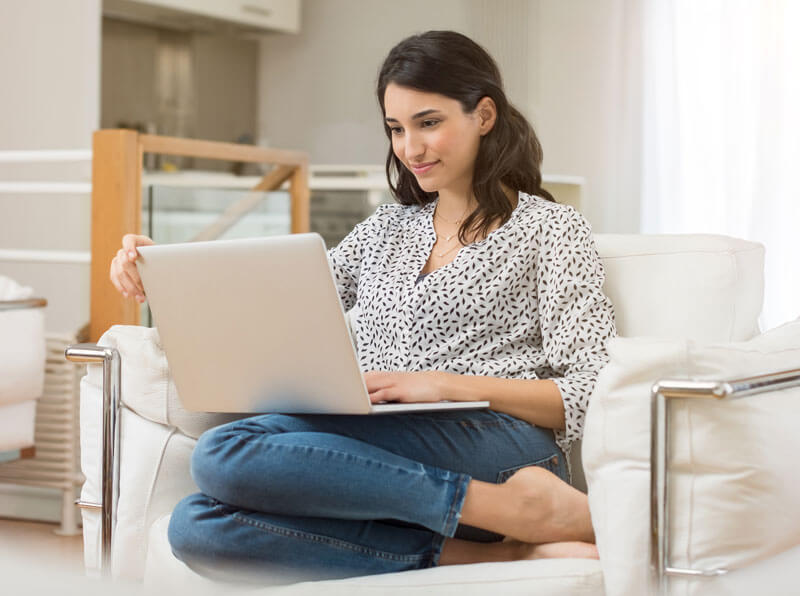 woman on laptop with her legs tucked under her on the couch
